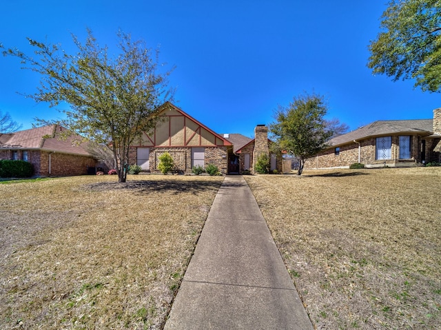 113 S Beltwoods Dr, Desoto, TX 75115 - tudor house with brick siding, a chimney, and a front lawn