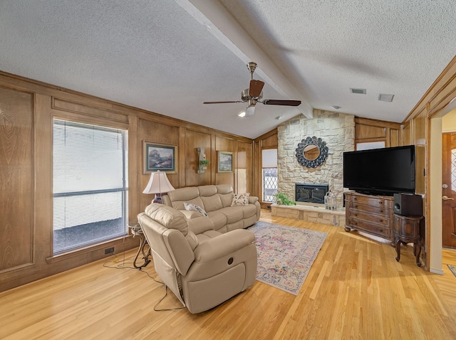 living room featuring visible vents, a fireplace, lofted ceiling with beams, and light wood finished floors