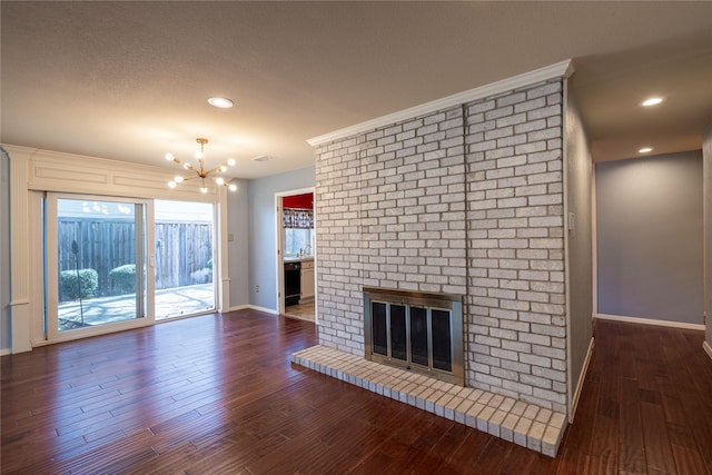 unfurnished living room featuring recessed lighting, dark wood-type flooring, baseboards, a brick fireplace, and an inviting chandelier