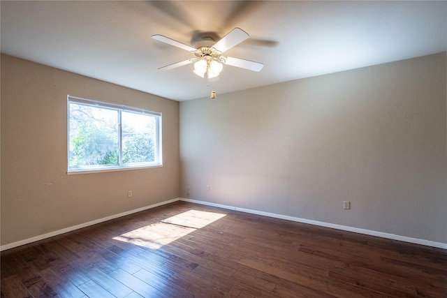 spare room with dark wood-style floors, a ceiling fan, and baseboards