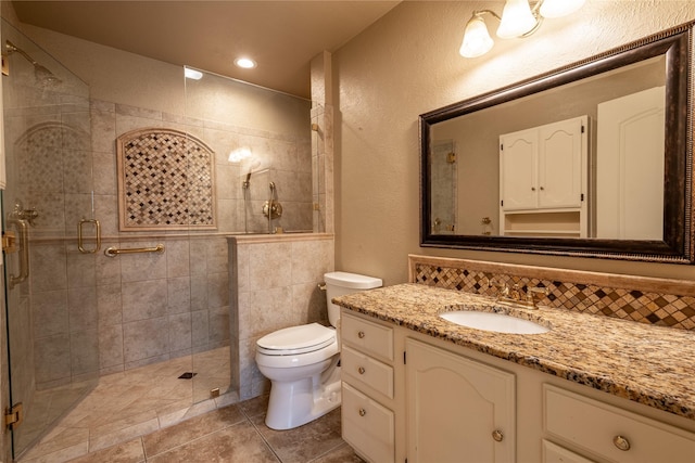 bathroom featuring a textured wall, tile patterned flooring, toilet, vanity, and a shower stall