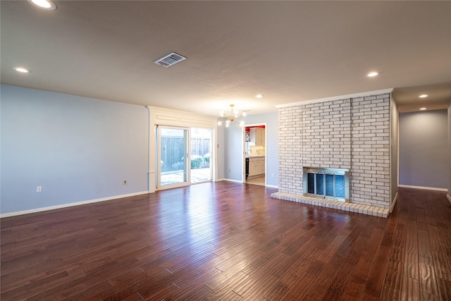 unfurnished living room with a chandelier, a fireplace, wood finished floors, visible vents, and baseboards