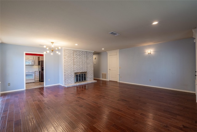 unfurnished living room with a brick fireplace, visible vents, a notable chandelier, and dark wood-style flooring