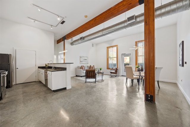 kitchen with visible vents, dark countertops, open floor plan, stainless steel appliances, and a sink