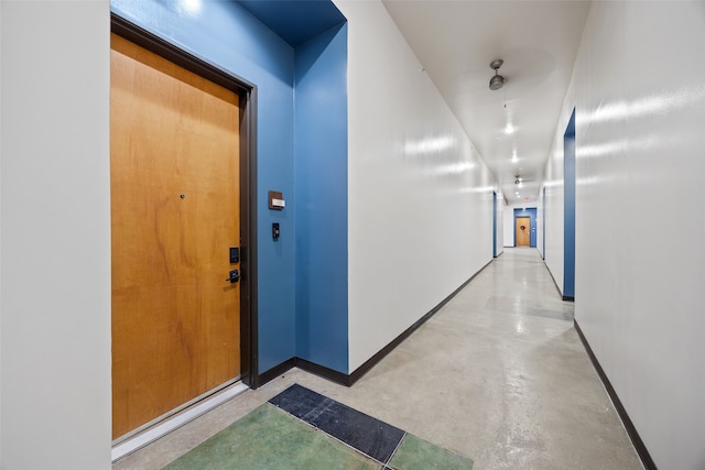 hall featuring finished concrete floors and baseboards