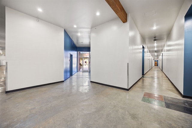 hallway featuring finished concrete flooring, recessed lighting, beam ceiling, and baseboards