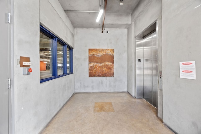 hallway featuring elevator and concrete floors