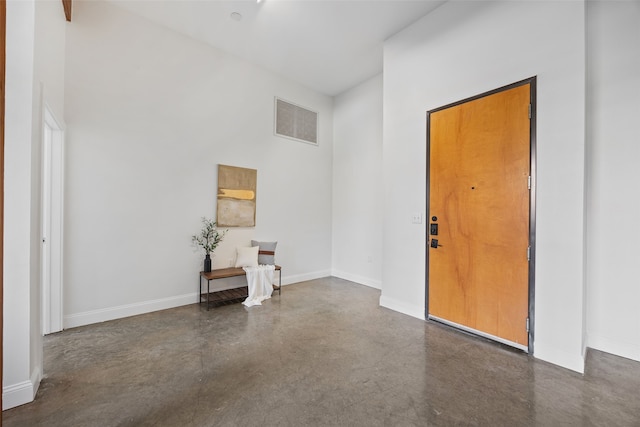 foyer entrance featuring baseboards, concrete floors, and visible vents