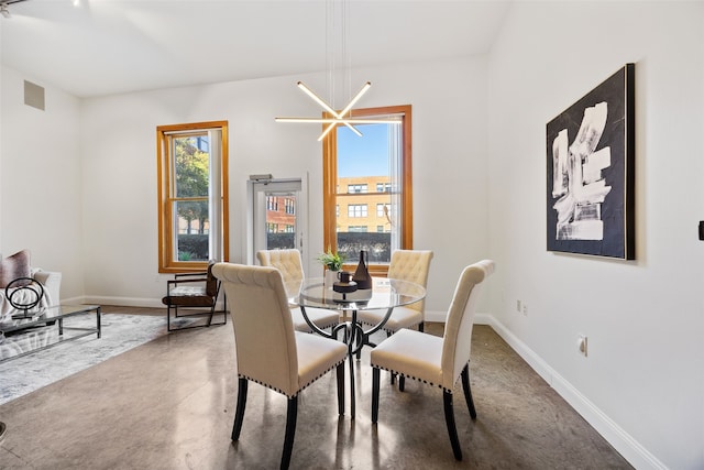 dining area with finished concrete floors, a chandelier, visible vents, and baseboards