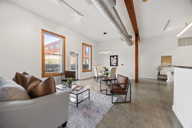 living area featuring visible vents, baseboards, finished concrete flooring, and track lighting