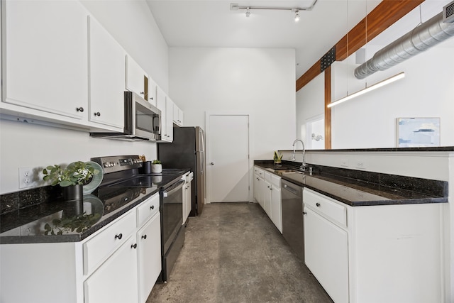 kitchen with concrete flooring, white cabinetry, stainless steel appliances, and a sink