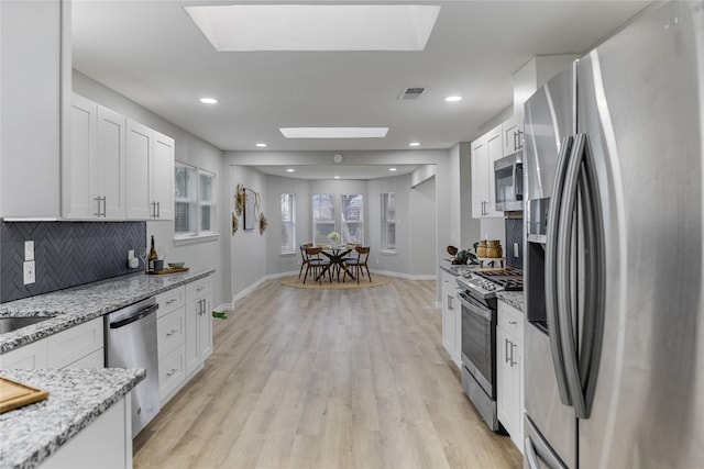 kitchen with white cabinetry, a skylight, visible vents, and appliances with stainless steel finishes