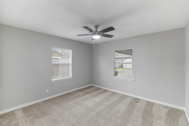 unfurnished room featuring a healthy amount of sunlight, ceiling fan, baseboards, and light colored carpet