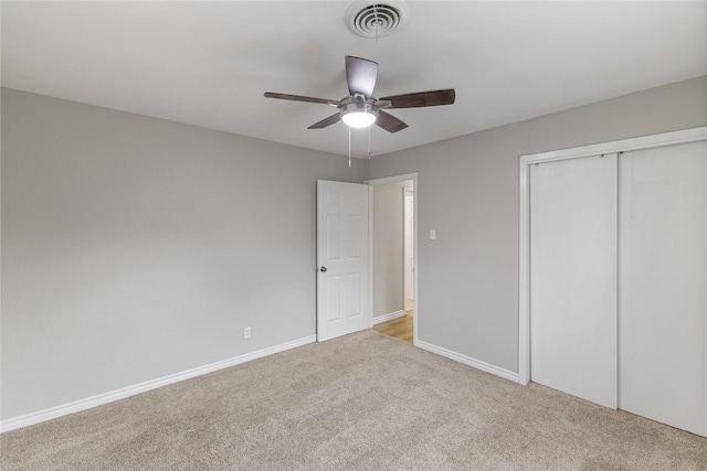 unfurnished bedroom with a closet, visible vents, light carpet, and baseboards