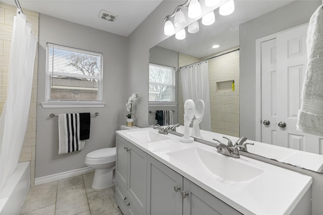 bathroom featuring toilet, double vanity, visible vents, and a sink