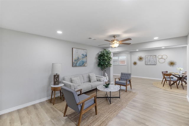 living room featuring light wood-type flooring, visible vents, baseboards, and recessed lighting