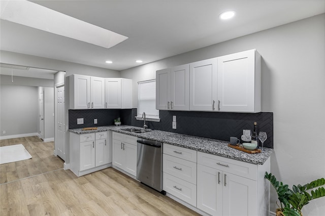 kitchen with dishwasher, backsplash, light stone countertops, light wood-style floors, and a sink