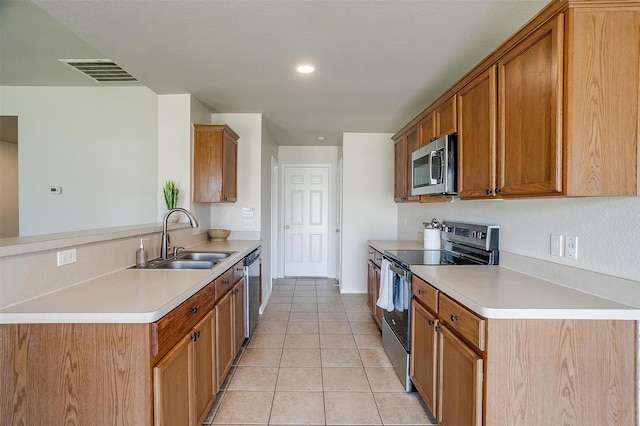 kitchen with visible vents, a peninsula, stainless steel appliances, light countertops, and a sink