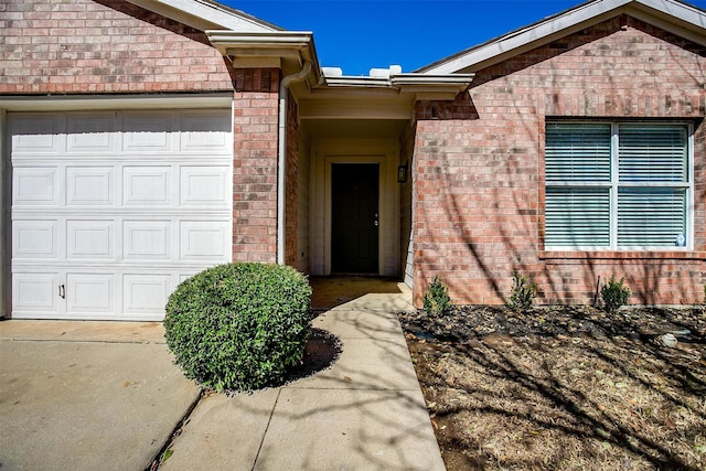 entrance to property with a garage and brick siding