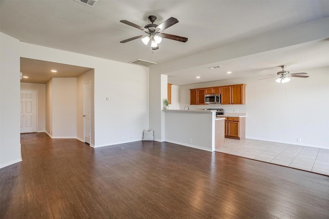 unfurnished living room with visible vents, ceiling fan, baseboards, and wood finished floors