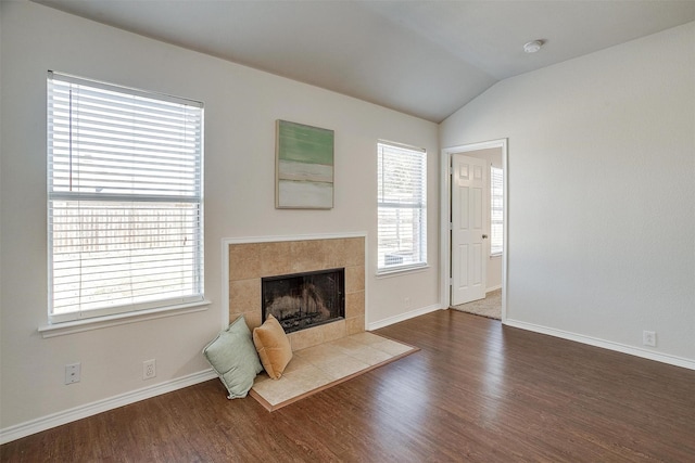 unfurnished living room with lofted ceiling, baseboards, a tiled fireplace, and wood finished floors