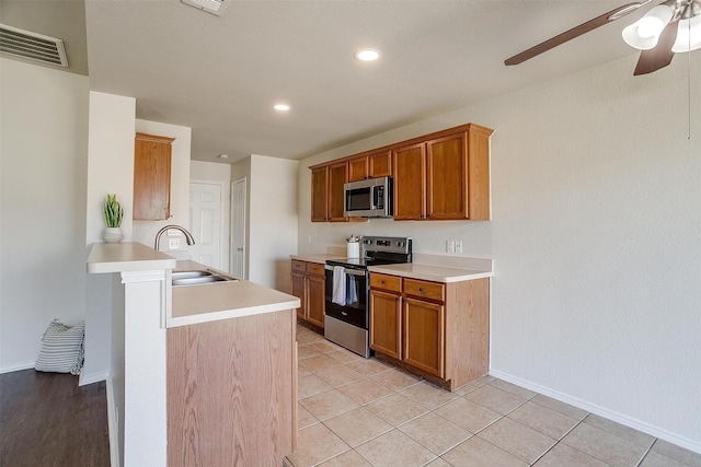 kitchen featuring brown cabinets, light countertops, visible vents, appliances with stainless steel finishes, and a sink