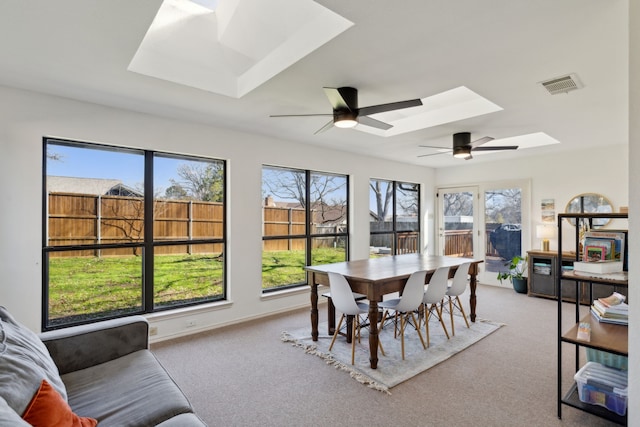 carpeted dining area featuring a skylight, visible vents, ceiling fan, and baseboards