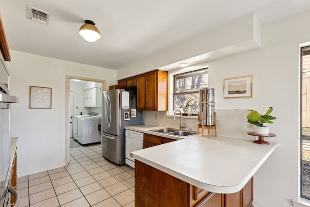 kitchen with visible vents, washer / clothes dryer, white dishwasher, light countertops, and a sink