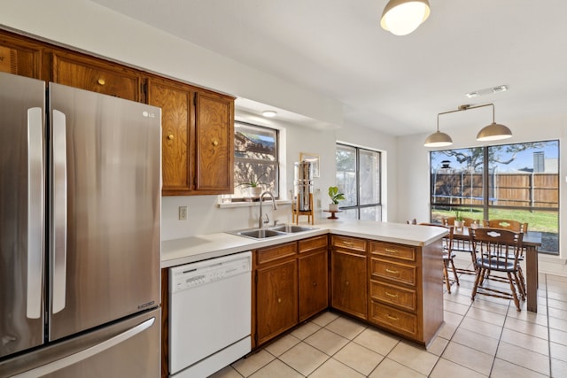 kitchen with white dishwasher, a peninsula, a sink, visible vents, and freestanding refrigerator