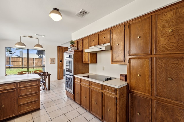 kitchen with black electric stovetop, visible vents, light countertops, brown cabinetry, and under cabinet range hood