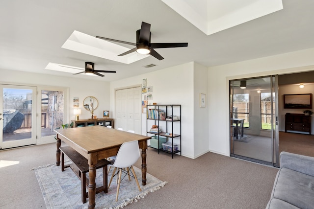 dining space featuring carpet floors, a skylight, visible vents, and a ceiling fan