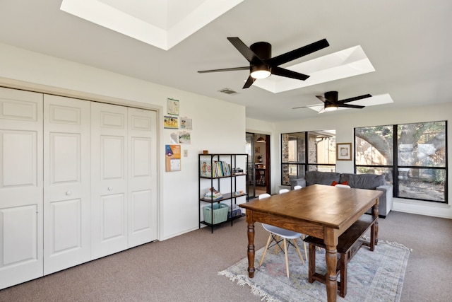 carpeted dining room with baseboards, a skylight, visible vents, and a ceiling fan