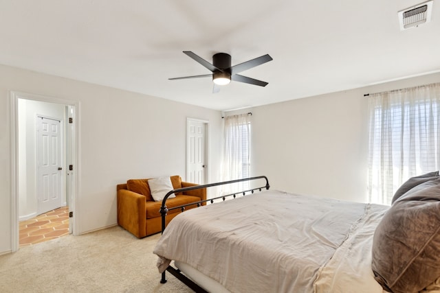 bedroom with light carpet, visible vents, and a ceiling fan