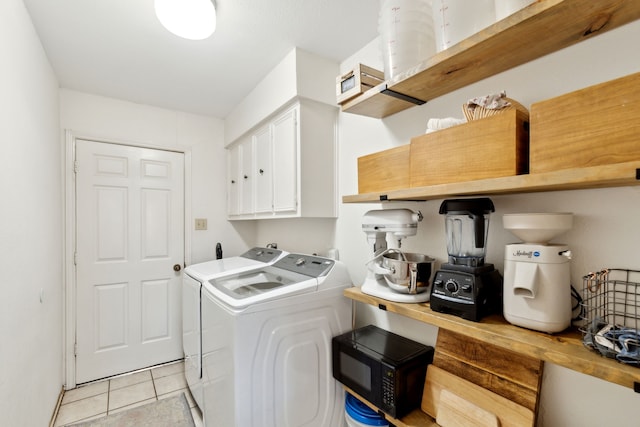 washroom with cabinet space, washer and clothes dryer, and light tile patterned floors