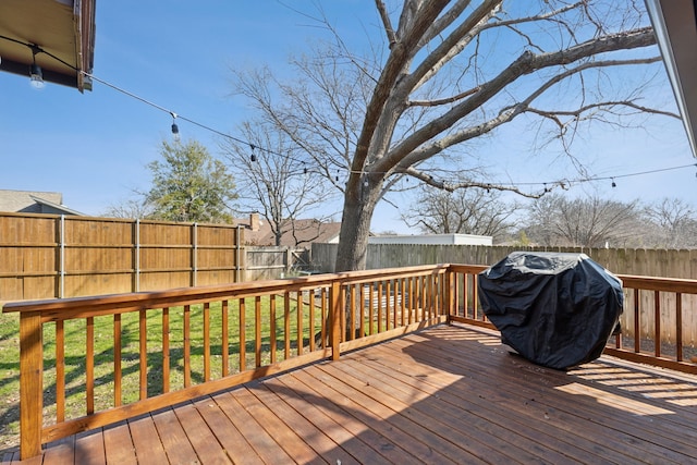 wooden deck with a fenced backyard and area for grilling