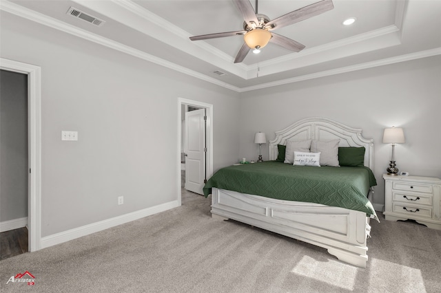 carpeted bedroom with ornamental molding, a tray ceiling, visible vents, and baseboards