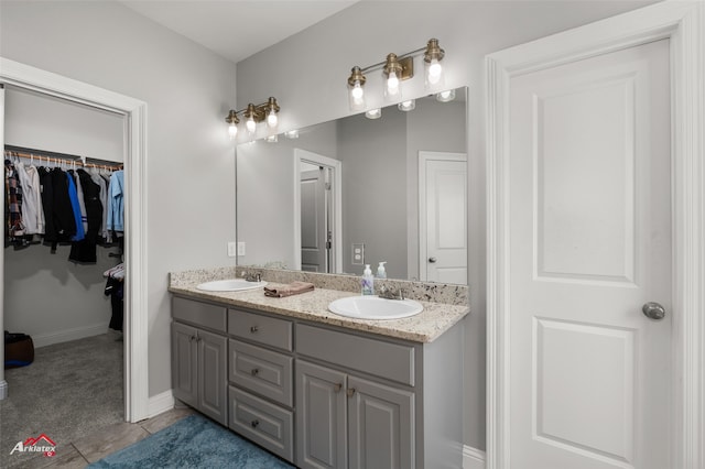 full bathroom featuring double vanity, a spacious closet, tile patterned flooring, and a sink