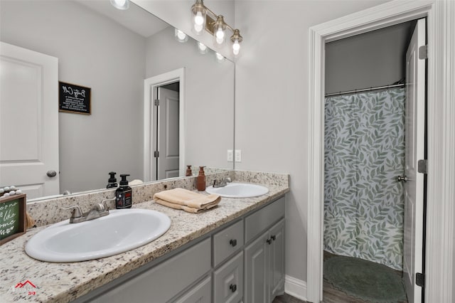 bathroom featuring baseboards, a sink, a shower with shower curtain, and double vanity