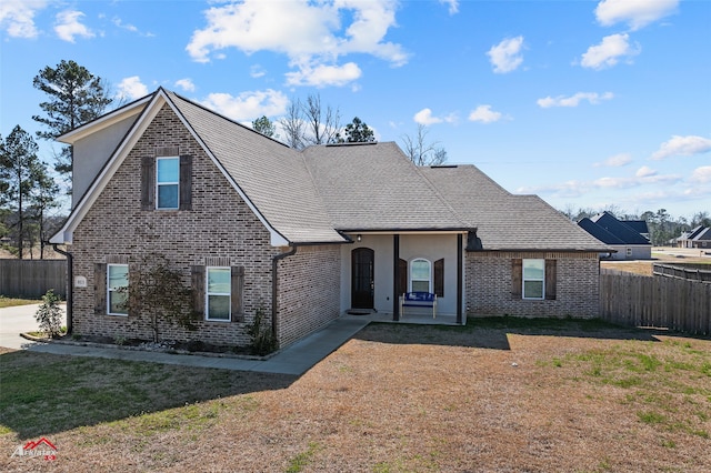 traditional-style house featuring brick siding, fence, and a front lawn