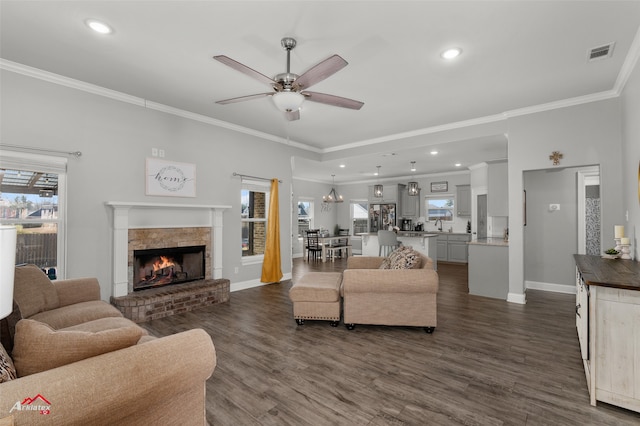 living room featuring dark wood-style floors, ornamental molding, visible vents, and a ceiling fan