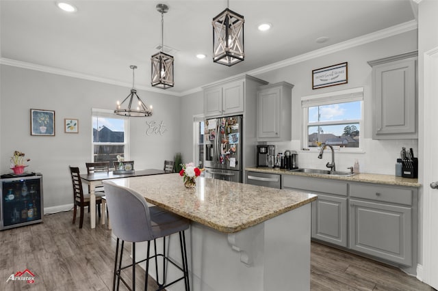 kitchen featuring dark wood-style floors, appliances with stainless steel finishes, a center island, gray cabinetry, and a sink