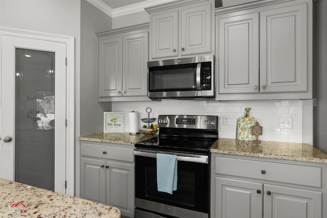 kitchen with ornamental molding, stainless steel appliances, tasteful backsplash, and light stone counters