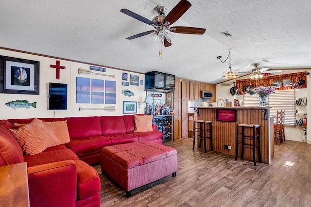 505 County Road 3420, Hawkins, TX 75765 - living area with visible vents, vaulted ceiling, a textured ceiling, wood finished floors, and bar area