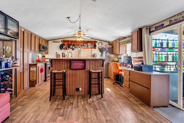 505 County Road 3420, Hawkins, TX 75765 - kitchen with light wood-type flooring, vaulted ceiling, stainless steel appliances, and a textured ceiling