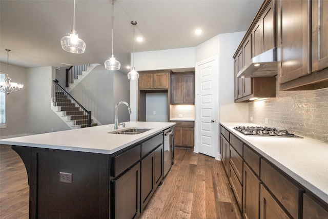 kitchen featuring under cabinet range hood, dark wood-type flooring, a sink, appliances with stainless steel finishes, and decorative light fixtures