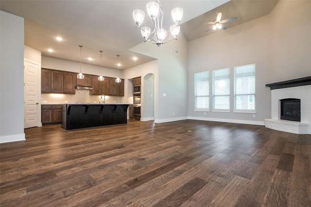 unfurnished living room with high vaulted ceiling, a fireplace, baseboards, and dark wood finished floors