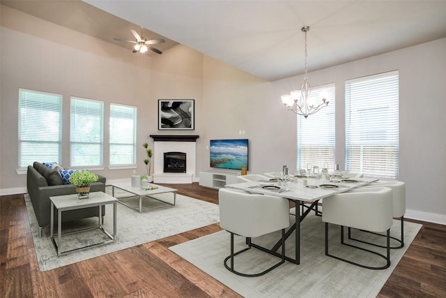 dining room featuring a glass covered fireplace, vaulted ceiling, baseboards, and wood finished floors