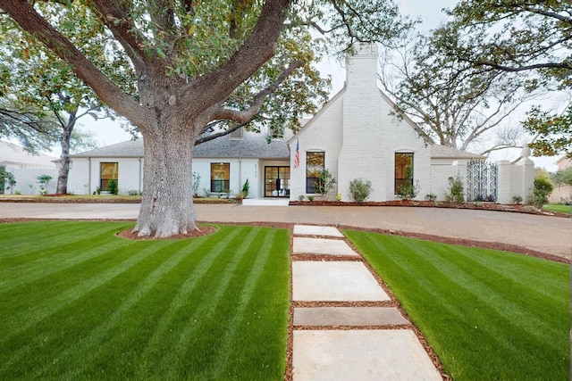 rear view of property featuring a yard, brick siding, and a chimney