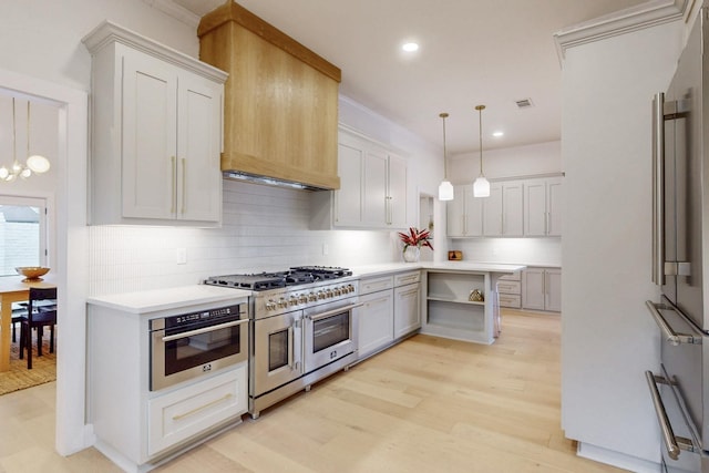 kitchen with light wood finished floors, stainless steel appliances, light countertops, pendant lighting, and backsplash