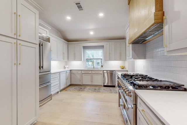 kitchen featuring light countertops, premium range hood, high end appliances, and visible vents